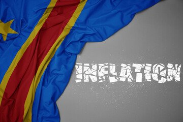 waving colorful national flag of democratic republic of the congo on a gray background with broken text inflation. 3d illustration