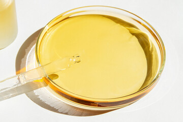Petri dish. With yellow liquid. With solution. Cosmetic pipette. Comedy bottle. On a white background.