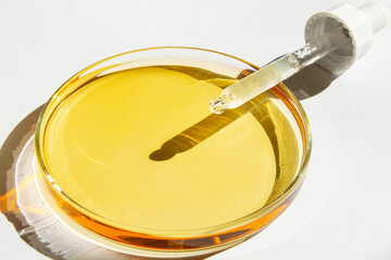 Petri dish. With yellow liquid. With solution. Cosmetic pipette. On a white background.