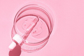Petri dish. With transparent gel. The pipette lies. Cosmetic dispenser. On a pink background.