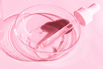 Petri dish. With transparent gel. With a pipette. Cosmetics bottle. On a pink background.