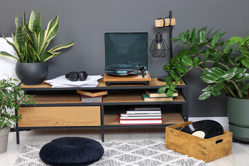 Stylish turntable with vinyl record on tv table in cozy room