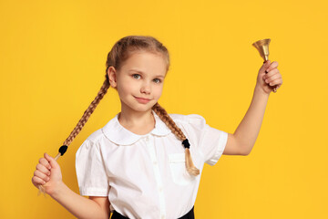 Pupil with school bell on yellow background