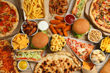 French fries, pizza and other fast food on wooden table, flat lay