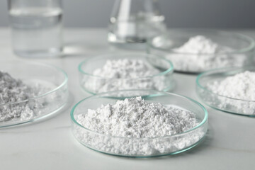 Many petri dishes with calcium carbonate powder on white table