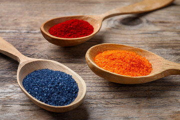 Many spoons with food coloring on wooden table, closeup