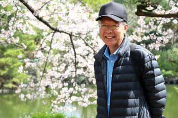 桜を背景に笑顔のシニア