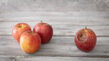 A red rotten disgusting apple separated of good ones. Bad and good separated.