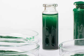 A solution or oil from spirulina in a jar. On a white background. Petri dishes with maxa or...
