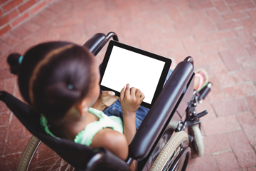 Young girl using digital computer sitting on wheelchair