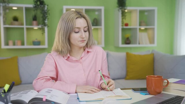 University girl with a focus problem.
University girl studying at home has trouble focusing. Something always comes to mind.
