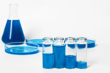 a set of flasks, jars for the laboratory with blue, blue liquid. Against the background of laboratory glassware. Petri dishes, flasks, test tubes. On a white, light background.