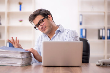 Young male employee and too much work in the office