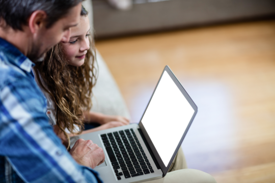 Father and daughter using laptop at home