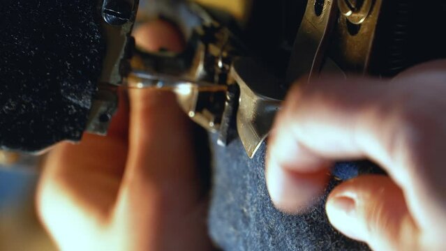 A female tailor seamstress hemming old jeans with vintage authentic machine in in a workshop repairing old denim clothes. Small family business, tailoring and repair of clothes, handmade, startup