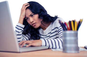 Concentrated Asian woman with hand on head using laptop