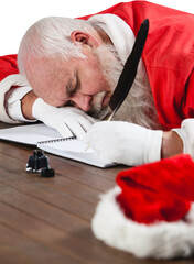 Santa Claus sleeping at desk while writing letter