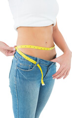 Mid section of a woman measuring waist in a big sized jeans