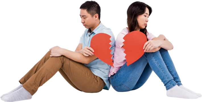 Sad couple holding broken heart pieces