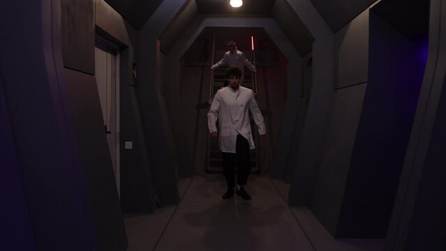 Worried staff of a spaceship running downstairs. Annoyed and scared men and a woman feeling unsafe while hearing alarm system with red flashes. High quality 4k footage