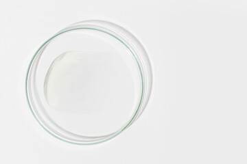 Petri dish on a light background. With a smear of white cream. Cosmetic cream, face mask, cream texture. View from above