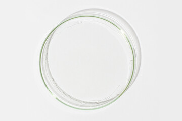 Petri dish on a light background. With a smear of clear gel. Cosmetic gel, lubricant, gel. View from above