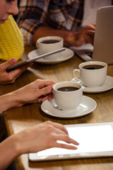 People with technologies and coffee cup in cafe