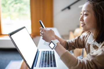 Woman using phone by laptop in classroom
