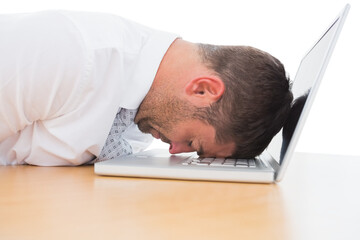Tired businessman resting head on laptop