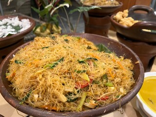 Big portion of fried vermicelli or rice noodle being served in a clay pot on a buffet table.