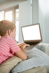 Boy using laptop while sitting on sofa in living room