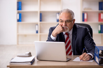Fototapeta premium Old male employee working in the office