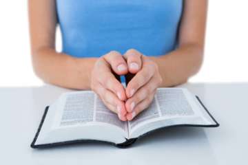 Woman praying while reading bible