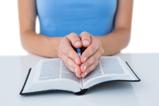 Woman praying while reading bible