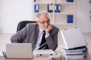 Naklejka premium Old male employee eating pizza in the office