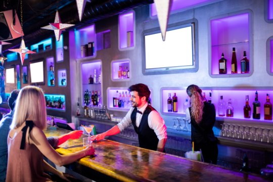 Smiling bartender serving drink to customer
