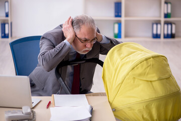 Old male employee looking after new born at workplace