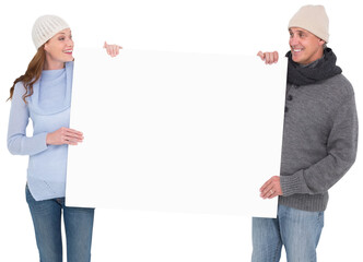 Casual couple in warm clothing holding poster