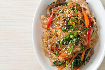 japchae or stir-fried Korean vermicelli noodles with vegetables and pork topped with white sesame