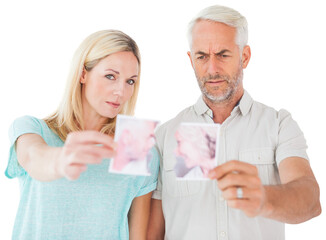 Unhappy couple holding two halves of torn photograph