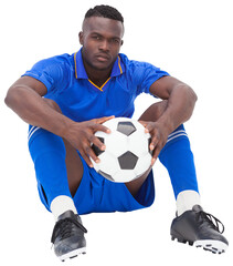 Football player in blue jersey sitting with ball