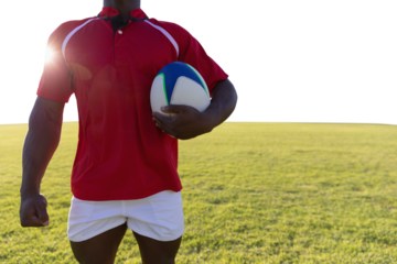 Male rugby player holding rugby ball in the ground