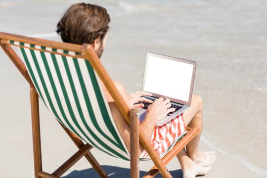 Man using laptop at beach - Powered by Adobe