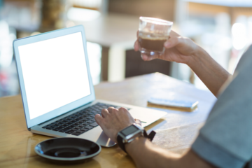 Man using a laptop while having cup of coffee