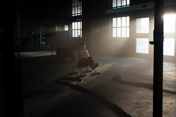 Young muscular sportsman doing straddle planche on parallel bars while training in the gym