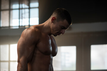 Obraz premium A young sexy athlete with perfect abs poses in the studio