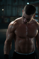 Fototapeta premium Muscular handsome man is shirtless at gym, posing on camera and flexing his muscles