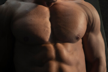 Naklejka premium Close-up top view of a shirtless muscular man doing leg raise exercise on the floor in the spoors gym