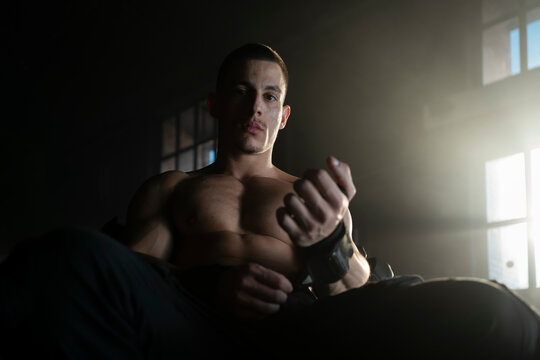 Shirtless bodybuilder man wrapping his hand with bandage inside the gym - Powered by Adobe