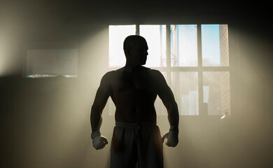 Shirtless boxer with muscular body standing in the training ground and preparing for shadow boxing